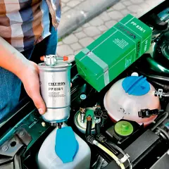 Wymiana filtra paliwa co ile? Nowy filtr paliwa Filtron PP 839/1 w rękach mechanika, obok silnika.