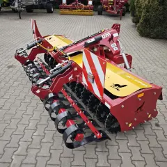 Czerwony wał crosskill z żółtymi elementami i logiem wilka, gotowy do pracy na polu.