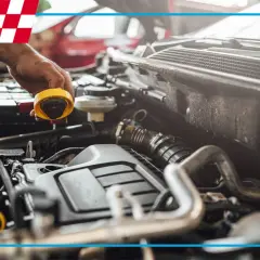 Mechanik sprawdza silnik, a na żółtym korku widać ślady **masła pod korkiem oleju**.