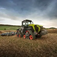 Potężny Claas Xerion z gąsienicami pracuje na polu, przygotowując ziemię do siewu.