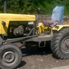 Żółty, domowej roboty traktor, który wygląda jakby ktoś chciał zobaczyć jak zrobić ciągnik sam.