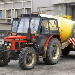 Czerwony Zetor 7245 z żółtym beczkowozem. Ile ma koni? Ten model zazwyczaj ma około 70 KM.