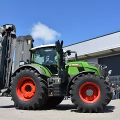 Zielony traktor Fendt 724 Vario z zamontowaną kosiarką, gotowy do pracy na polu.