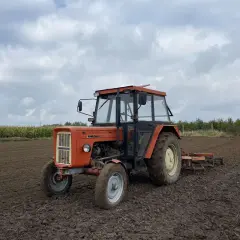 Pomarańczowy Ursus C-360 na polu, gotowy do pracy. Zastanawiasz się, ile oleju do silnika C-360 potrzebujesz?