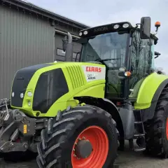 Ciągnik Claas Axion 810 w kolorze limonkowym, gotowy do pracy na polu.