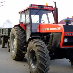Czerwony Ursus 1604 z przyczepą załadowaną workami, gotowy do pracy na gospodarstwie.