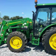 Zielony ciągnik John Deere 5075E z ładowaczem czołowym, gotowy do pracy na farmie.