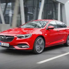 Czerwony Opel Insignia 2.0 CDTI pędzi ulicą miasta.