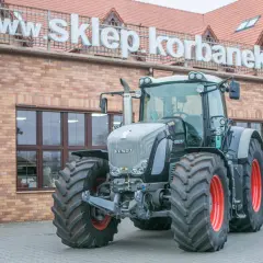 Potężny Fendt 936 Vario, gotowy do pracy na polu, przed budynkiem sklepu.