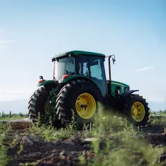 Zielony traktor John Deere na polu, gotowy do pracy. Właściwe płyny eksploatacyjne zapewniają jego niezawodność.
