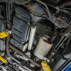 Podnośnik samochodowy podtrzymuje auto, ukazując podwozie z układem wydechowym i zbiornikiem paliwa. Czas na wypalanie DPF.