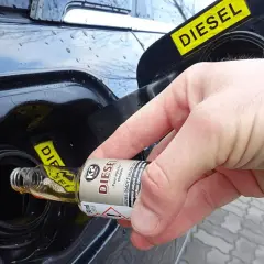 Dłoń wlewa dodatek do benzyny do baku samochodu z napisem DIESEL.