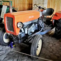 Pomarańczowy traktor SAM, znany jako esiok, z charakterystycznym grillem i silnikiem.