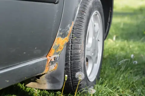 Widoczne ogniska rdzy na progu samochodu, wskazujące na potrzebę usuwania rdzy z samochodu.