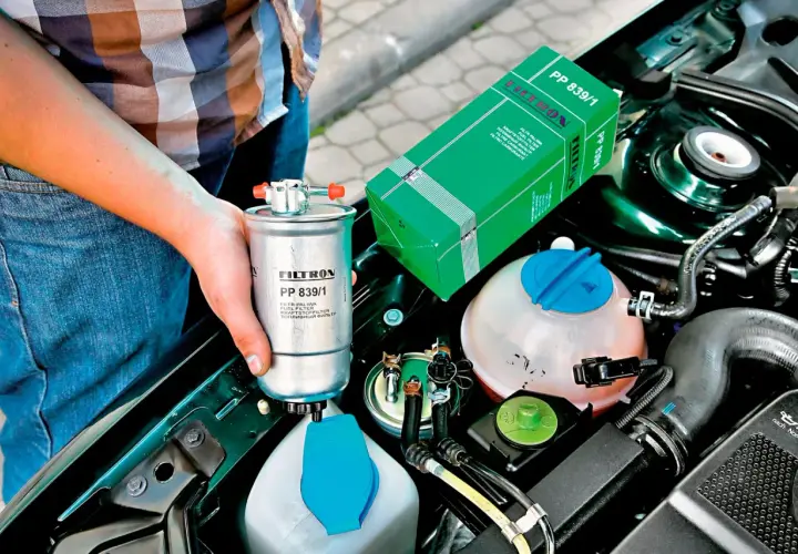 Wymiana filtra paliwa co ile? Nowy filtr paliwa Filtron PP 839/1 w rękach mechanika, obok silnika.