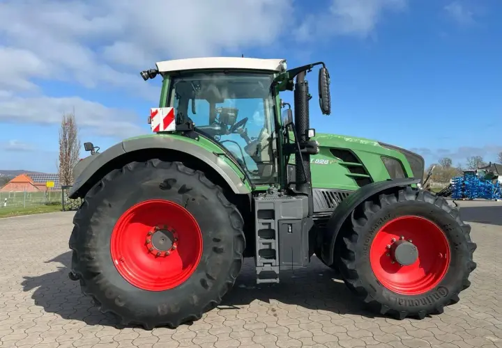 Zielony traktor Fendt 828 V z czerwonymi felgami, gotowy do pracy na polu.