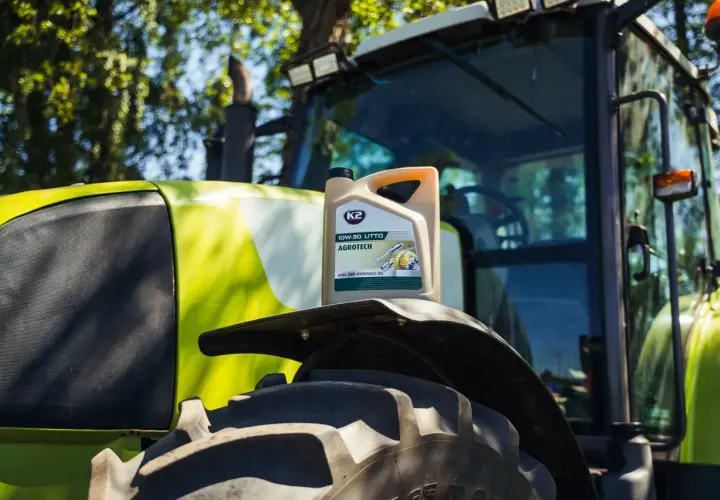 Kanister oleju K2 AGROTECH 10W-30 UTTO na błotniku zielonego traktora.