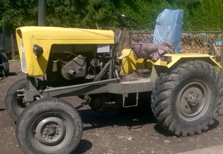 Żółty, domowej roboty traktor, który wygląda jakby ktoś chciał zobaczyć jak zrobić ciągnik sam.