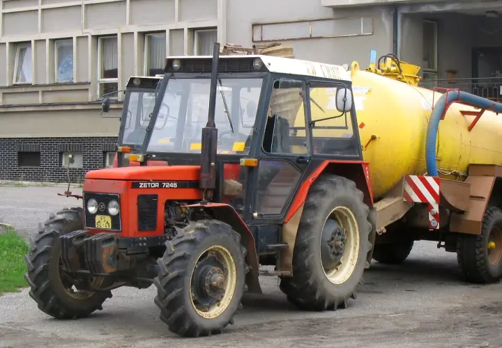 Czerwony Zetor 7245 z żółtym beczkowozem. Ile ma koni? Ten model zazwyczaj ma około 70 KM.