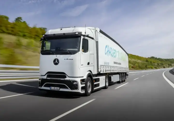 Biały elektryczny ciągnik siodłowy eActros jedzie po autostradzie. Zastanawiasz się, ile waży ciągnik siodłowy? Ten model jest gotowy na przyszłość transportu.
