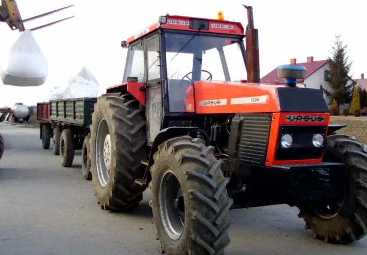 Czerwony Ursus 1604 z przyczepą załadowaną workami, gotowy do pracy na gospodarstwie.