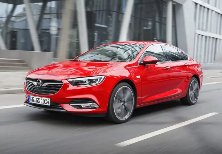 Czerwony Opel Insignia 2.0 CDTI pędzi ulicą miasta.