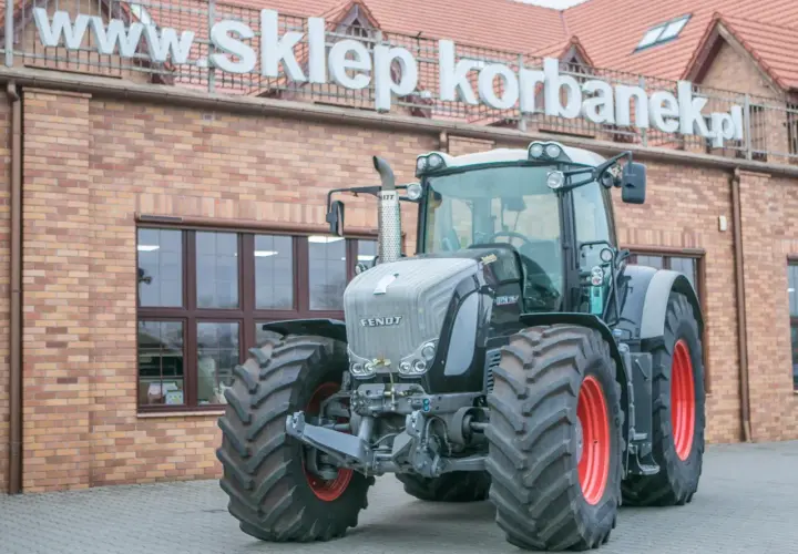 Potężny Fendt 936 Vario, gotowy do pracy na polu, przed budynkiem sklepu.
