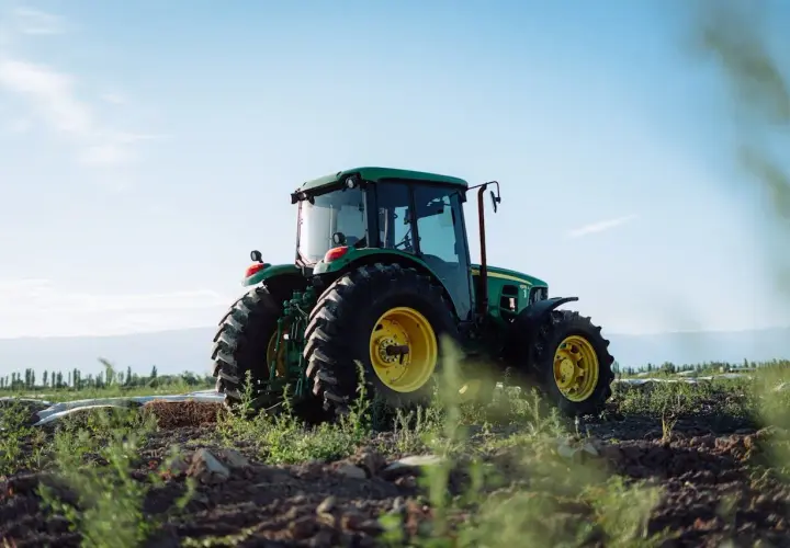 Zielony traktor John Deere na polu, gotowy do pracy. Właściwe płyny eksploatacyjne zapewniają jego niezawodność.