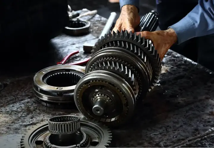 Mechanik składa elementy skrzyni biegów. Zastanawiasz się, ile kosztuje wymiana skrzyni biegów?