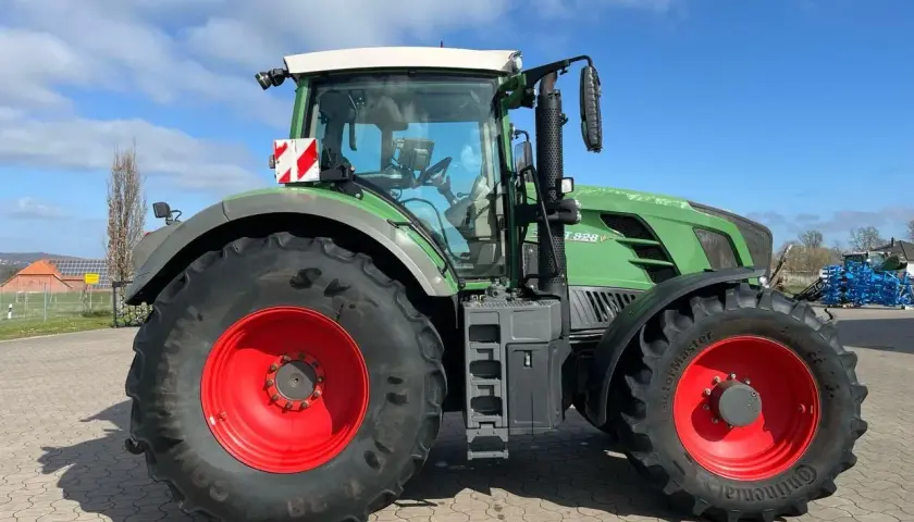 Zielony traktor Fendt 828 V z czerwonymi felgami, gotowy do pracy na polu.