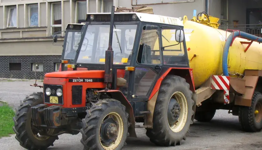 Czerwony Zetor 7245 z żółtym beczkowozem. Ile ma koni? Ten model zazwyczaj ma około 70 KM.