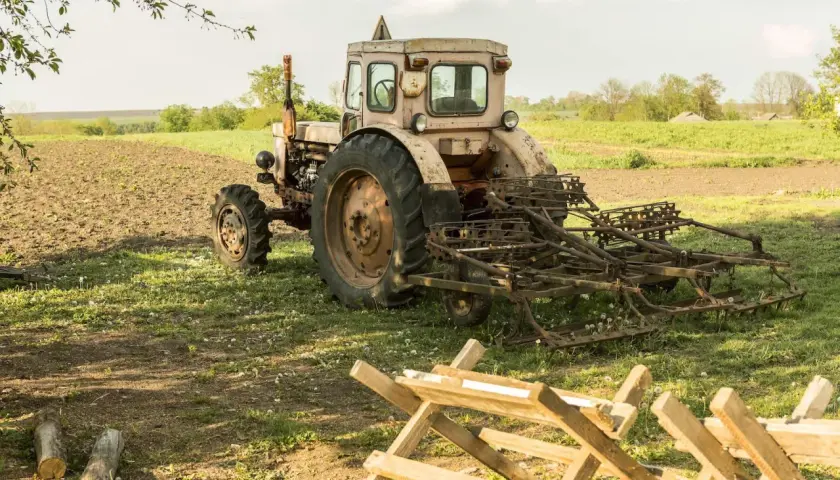 Stary traktor z pługiem na polu. Warto wiedzieć, jak przerejestrować ciągnik po śmierci właściciela, by móc dalej pracować.
