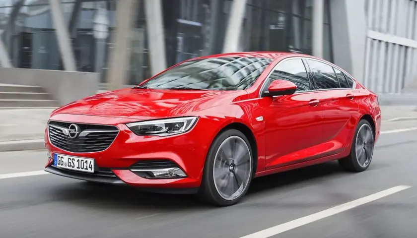 Czerwony Opel Insignia 2.0 CDTI pędzi ulicą miasta.