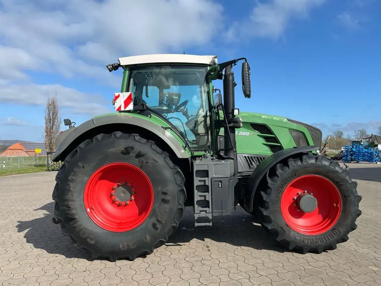 Zielony traktor Fendt 828 V z czerwonymi felgami, gotowy do pracy na polu.