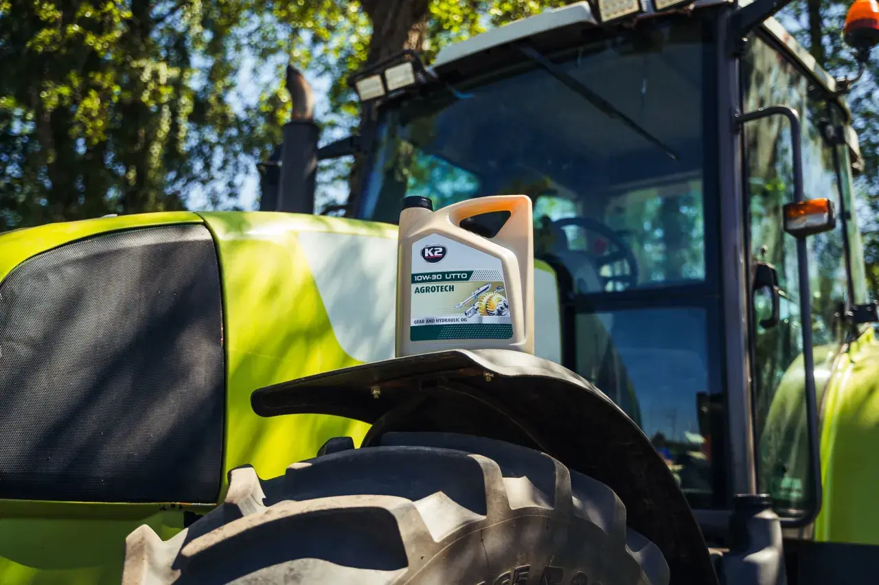 Kanister oleju K2 AGROTECH 10W-30 UTTO na błotniku zielonego traktora.