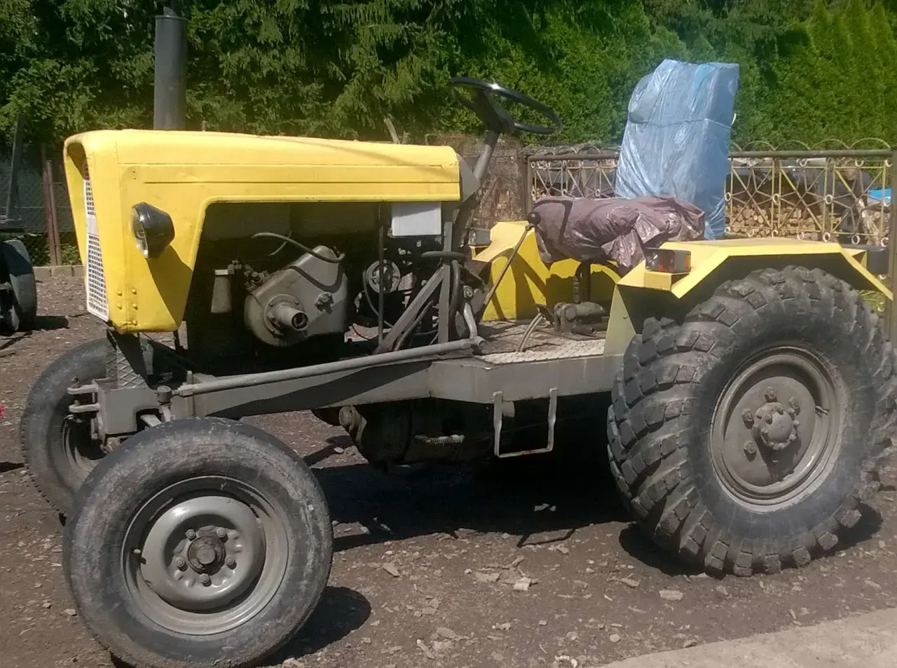 Żółty, domowej roboty traktor, który wygląda jakby ktoś chciał zobaczyć jak zrobić ciągnik sam.