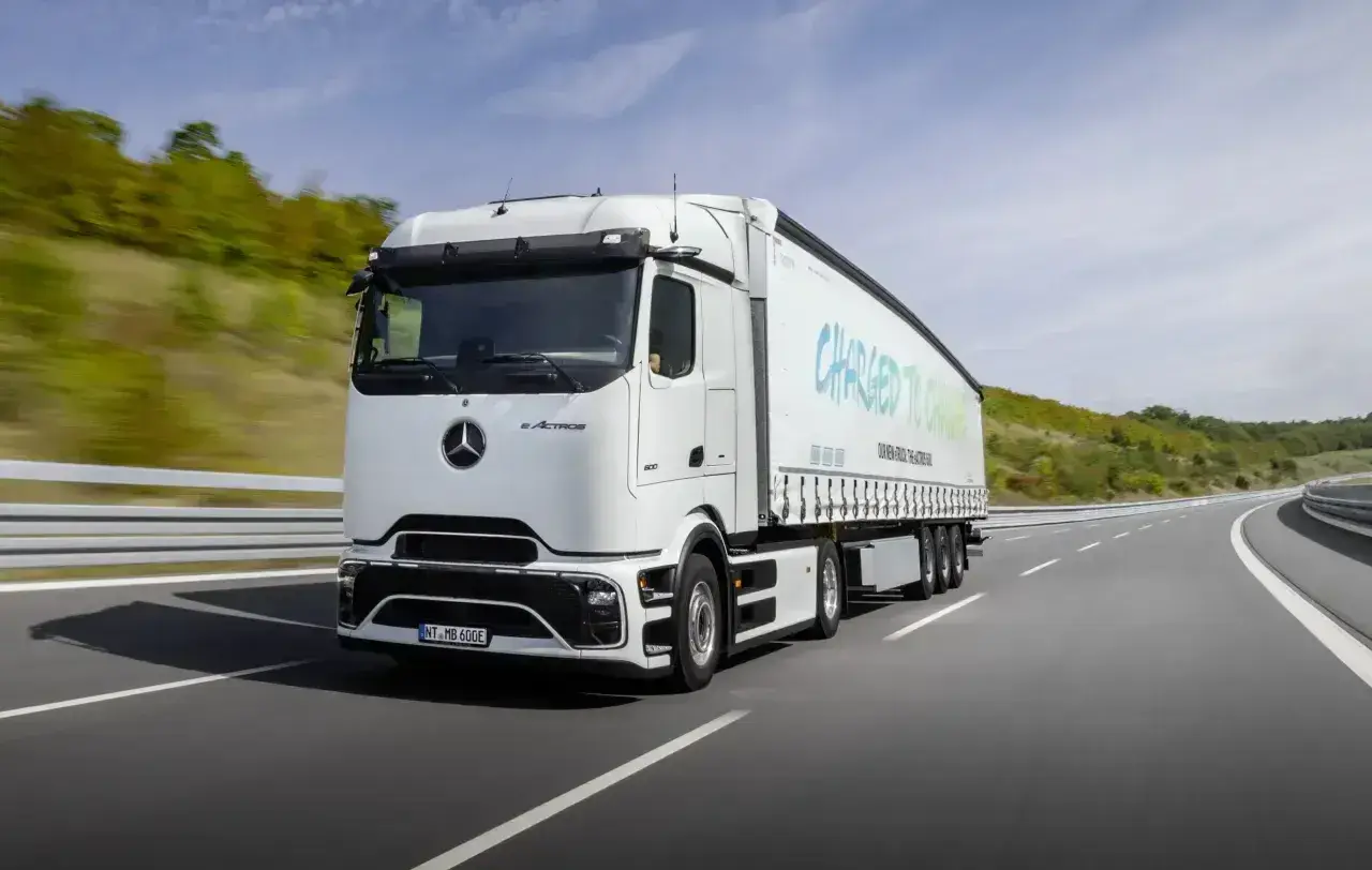Biały elektryczny ciągnik siodłowy eActros jedzie po autostradzie. Zastanawiasz się, ile waży ciągnik siodłowy? Ten model jest gotowy na przyszłość transportu.