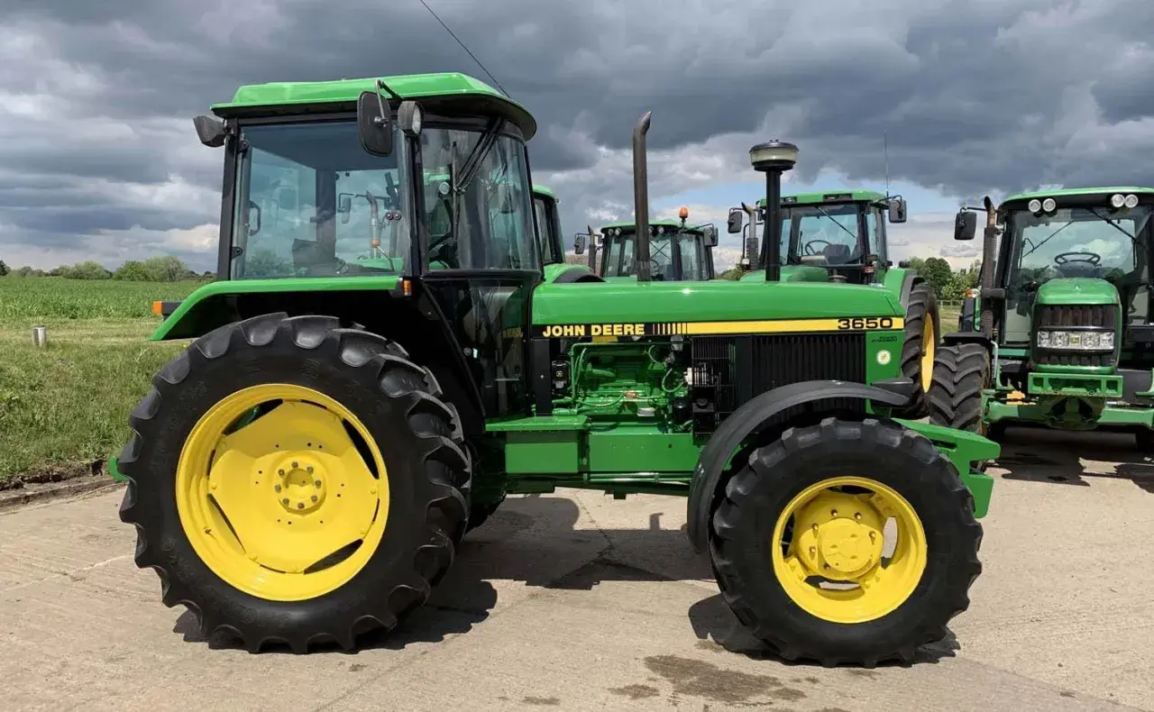 Zielony John Deere 3650 z żółtymi felgami, gotowy do pracy na polu.