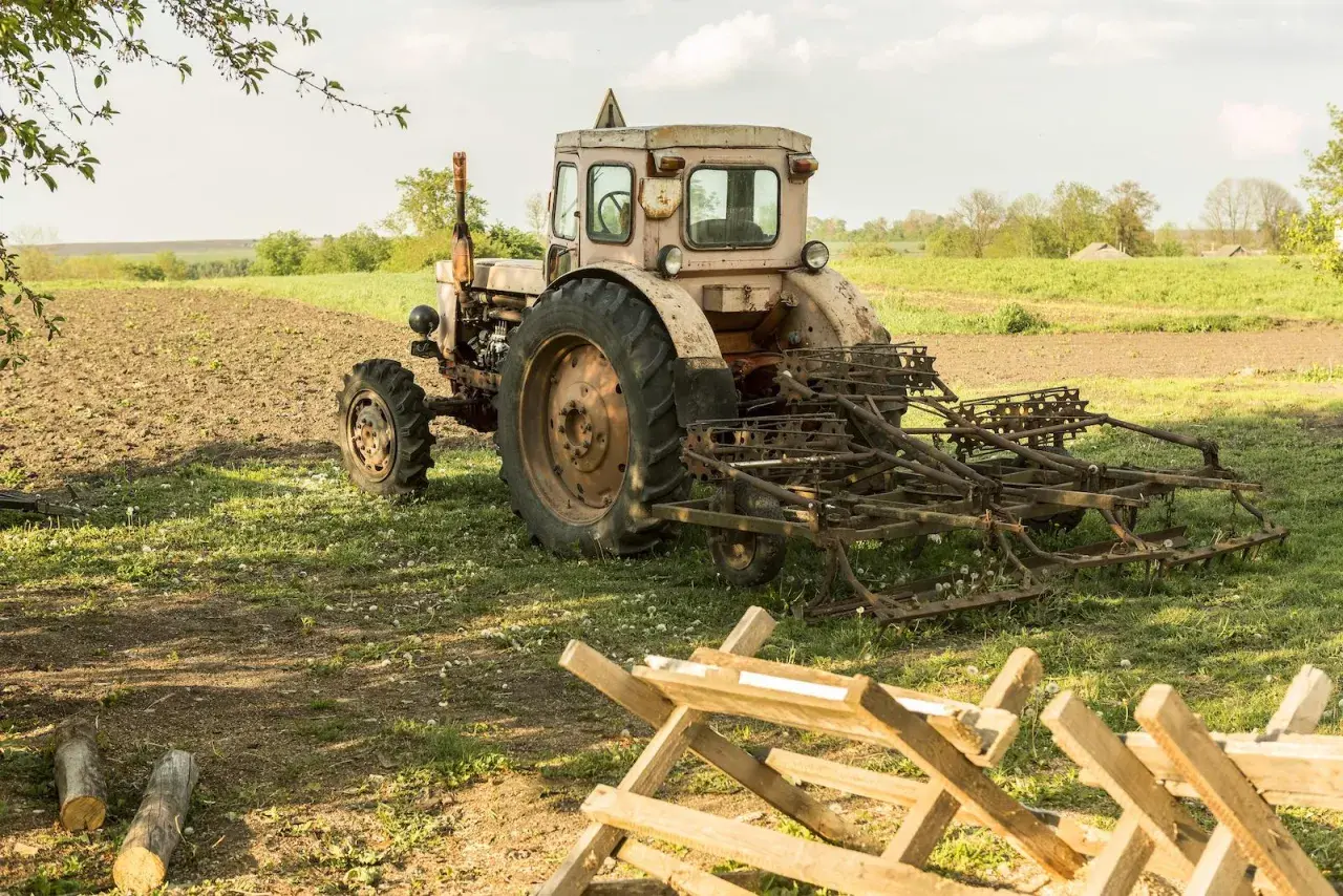 Stary traktor z pługiem na polu. Warto wiedzieć, jak przerejestrować ciągnik po śmierci właściciela, by móc dalej pracować.