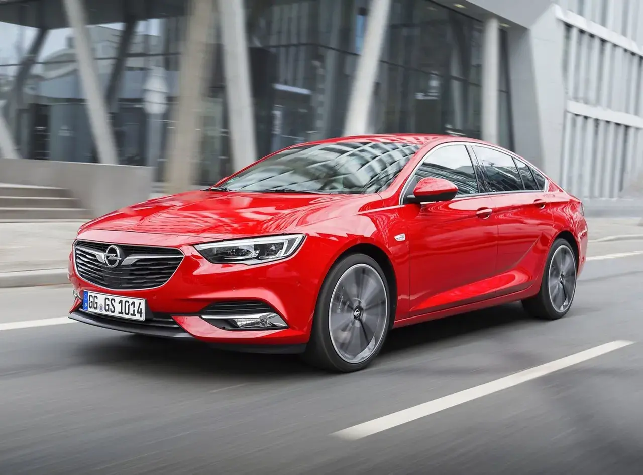 Czerwony Opel Insignia 2.0 CDTI pędzi ulicą miasta.