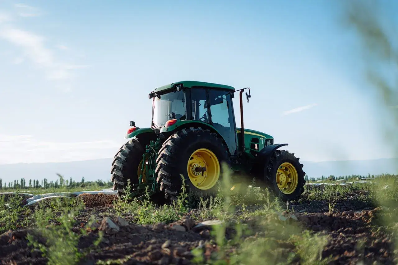 Zielony traktor John Deere na polu, gotowy do pracy. Właściwe płyny eksploatacyjne zapewniają jego niezawodność.