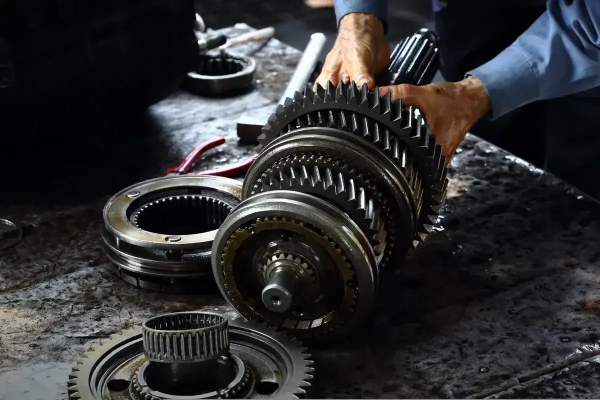 Mechanik składa elementy skrzyni biegów. Zastanawiasz się, ile kosztuje wymiana skrzyni biegów?