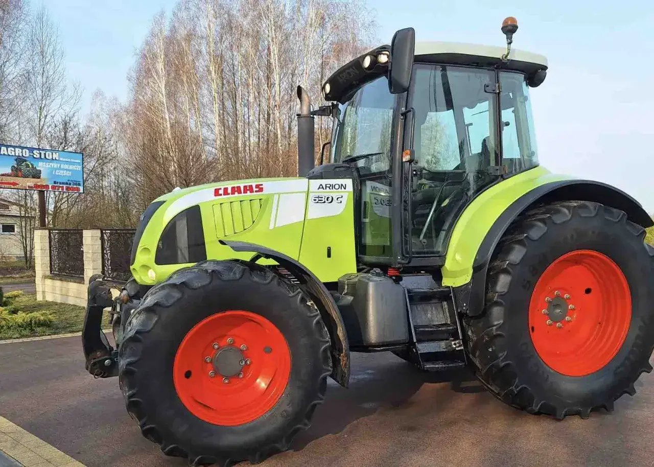 Jasnozielony traktor Claas Arion 630 G z pomarańczowymi felgami, gotowy do pracy na polu.