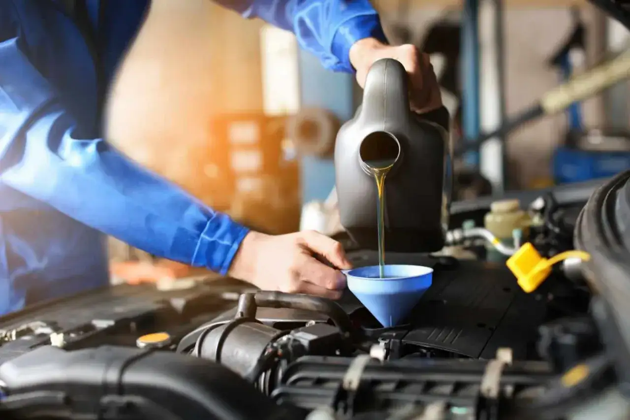 Mechanik wlewa olej do silnika. Zastanawiasz się, ile trwa wymiana oleju? Zazwyczaj to szybka czynność.