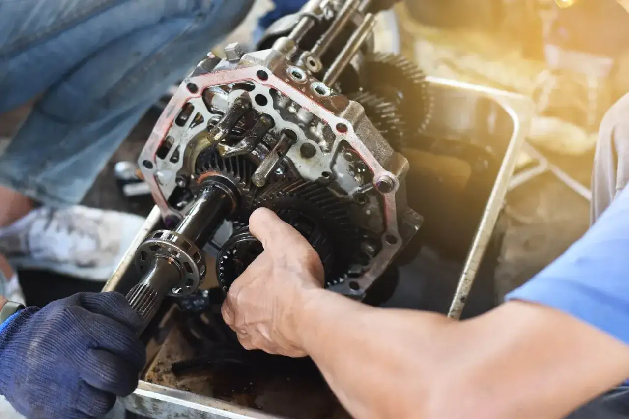 Mechanik pracuje nad skrzynią biegów, zastanawiając się, ile kosztuje wymiana skrzyni biegów.