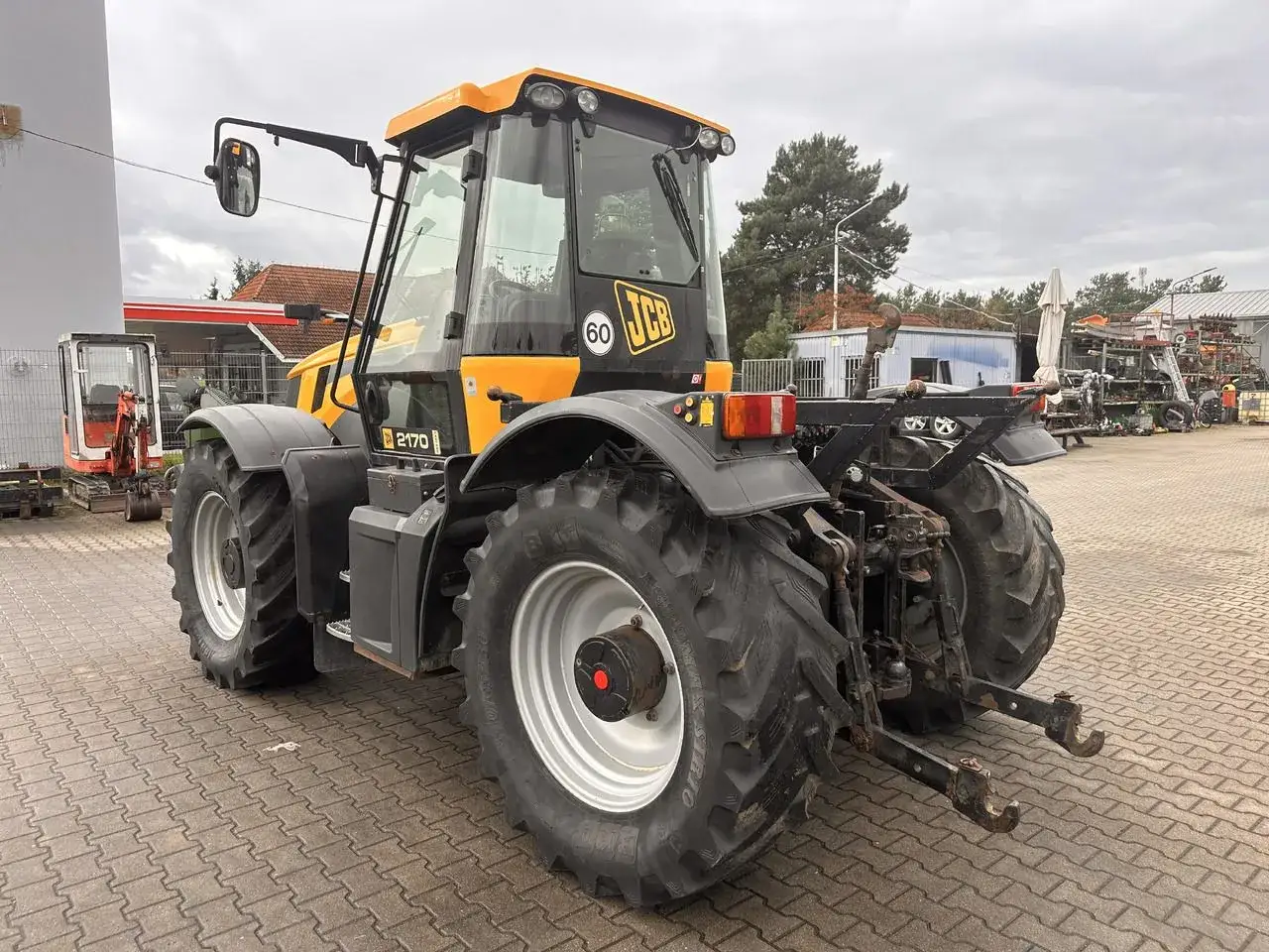 Żółty traktor JCB 2170, idealny dla szukających najtańszych ciągników rolniczych używanych. Gotowy do pracy na polu.