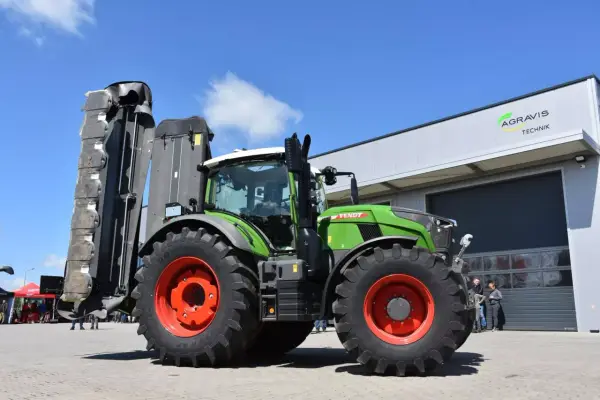 Zielony traktor Fendt 724 Vario z zamontowaną kosiarką, gotowy do pracy na polu.