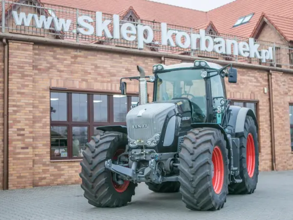 Potężny Fendt 936 Vario, gotowy do pracy na polu, przed budynkiem sklepu.